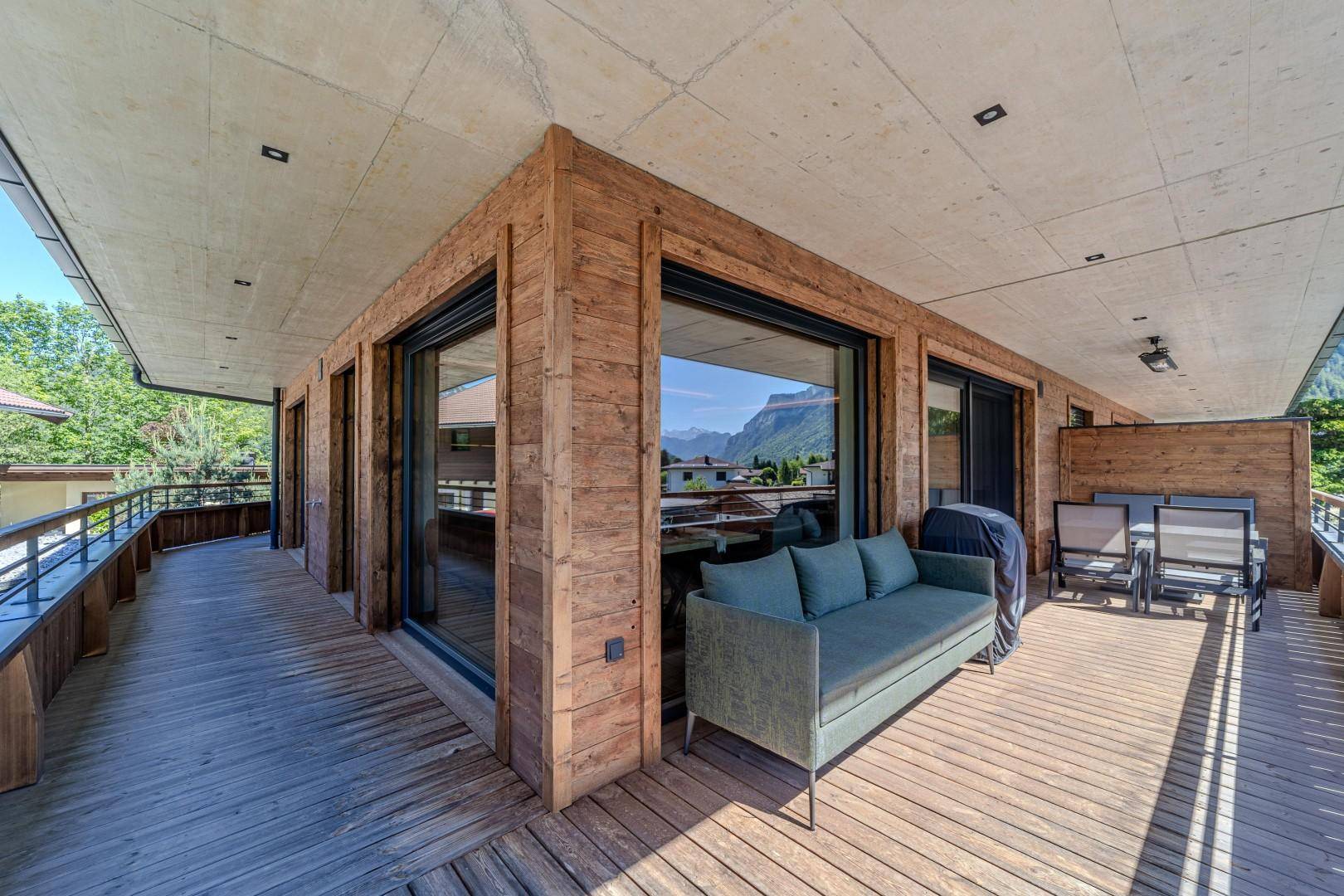 Großer Holzbalkon mit Sitzgelegenheiten und weitem Blick auf die umliegende Berglandschaft.