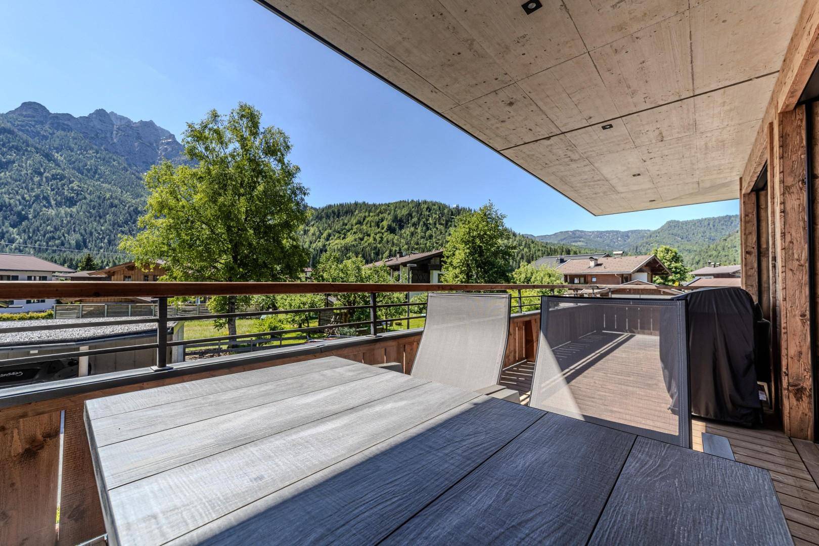 Großer Holzbalkon mit Sitzgelegenheiten und weitem Blick auf die umliegende Berglandschaft.