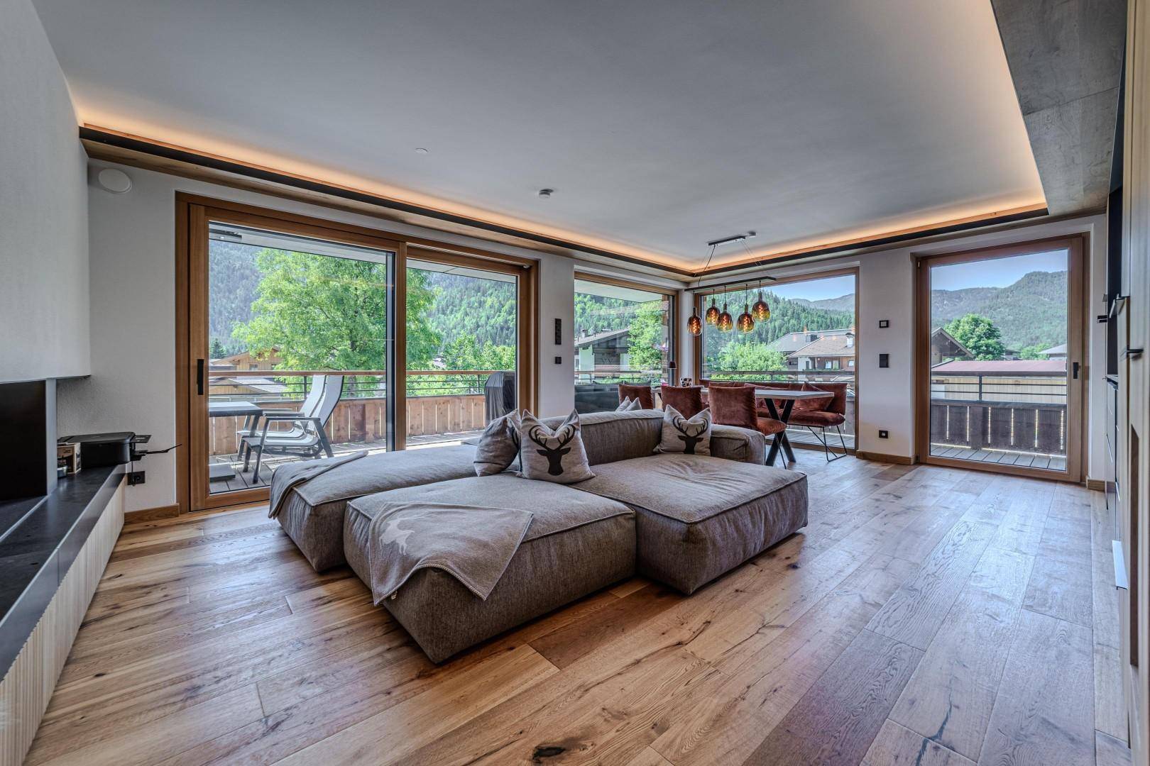 Heller Wohnbereich mit großzügigen Fensterfronten, Holzboden und Zugang zu zwei Balkonen.