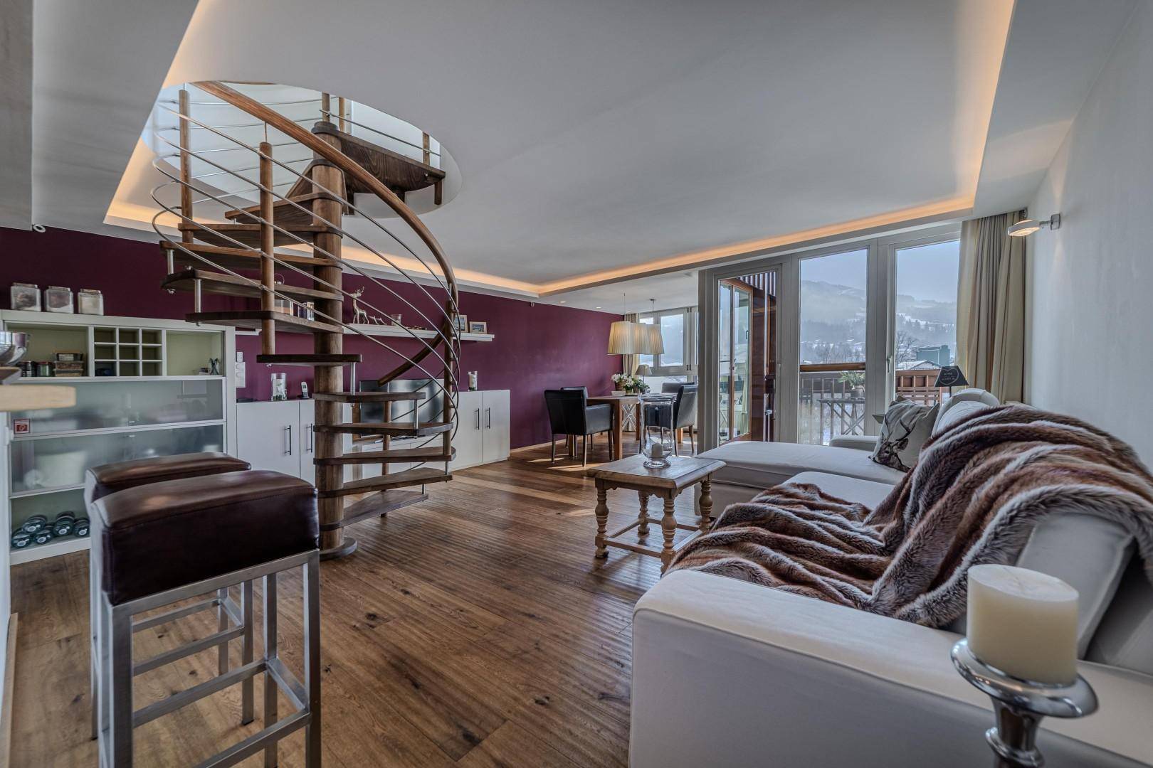 Offener Wohn- und Essbereich mit eleganter Holzwendeltreppe, Holzboden und Zugang zum Balkon.