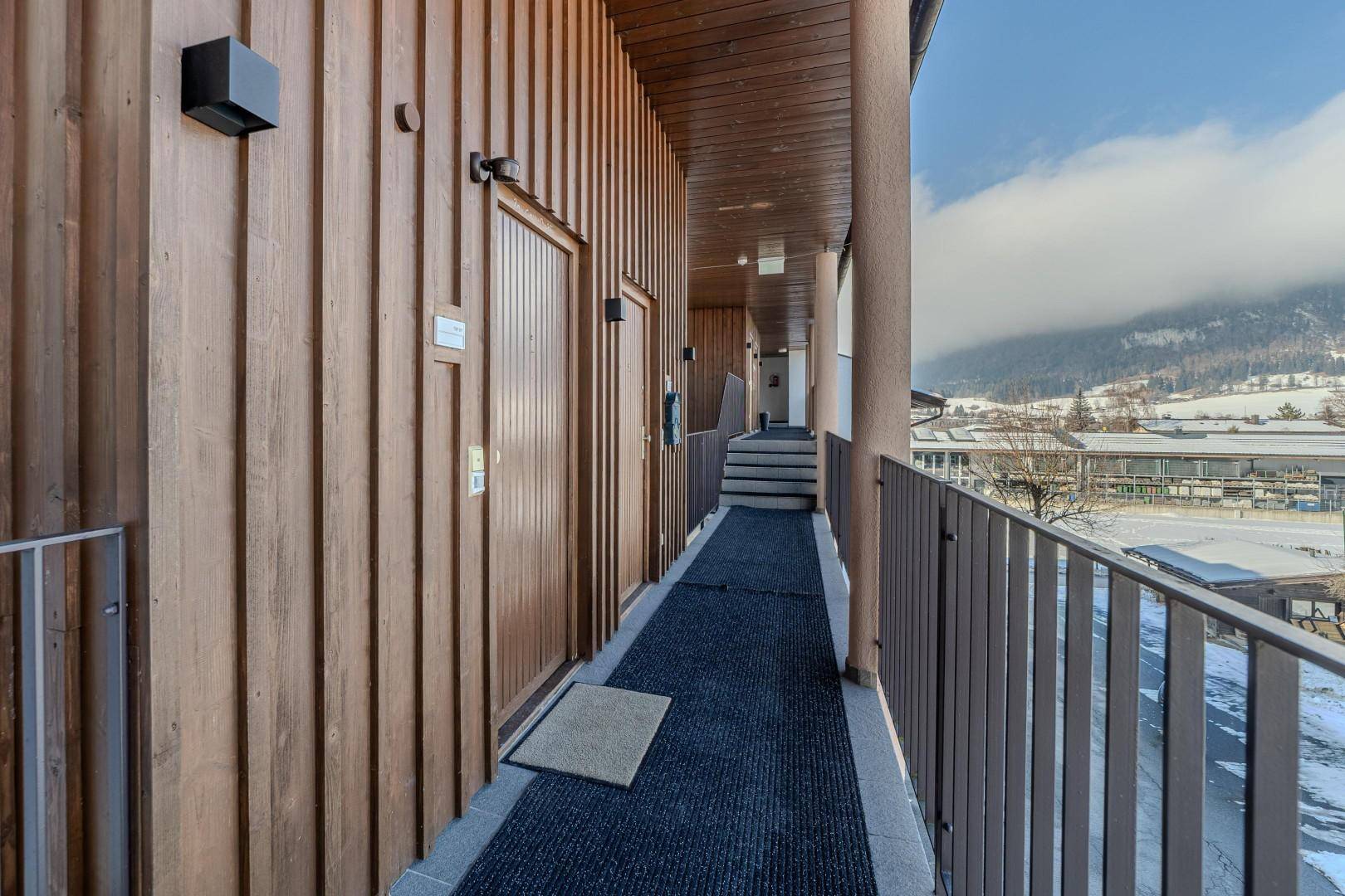 Heller Außenflur mit Holzverkleidung und Blick auf die verschneite Landschaft von der Balustrade.