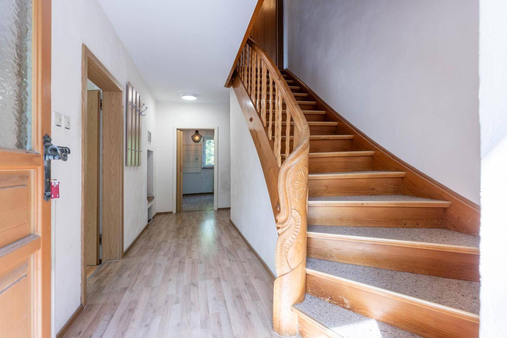 Heller Flur mit Holztreppe und Holzboden, der zu den oberen Etagen führt.
