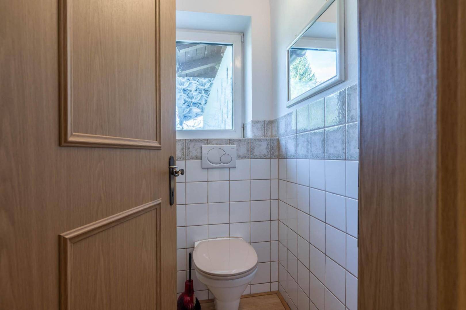 Separates WC mit Fenster, Wand-WC und hellen Fliesen, praktisch und gut beleuchtet.