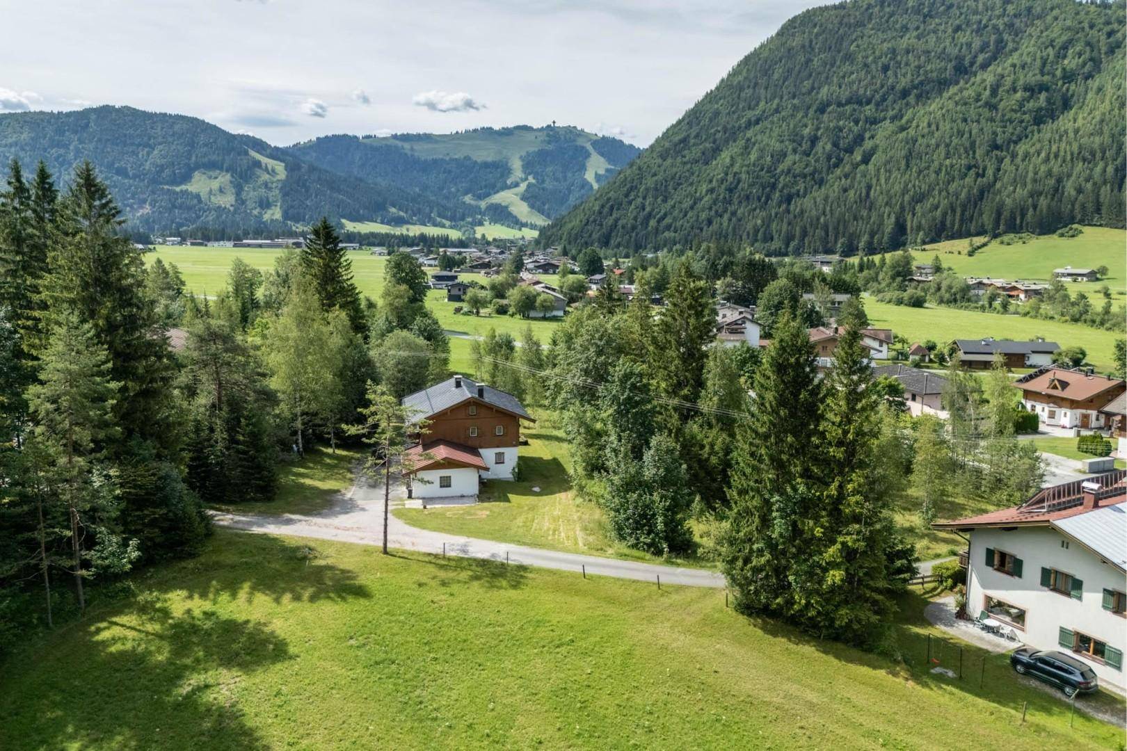 Weitläufige Ansicht eines Hauses in einer ländlichen Umgebung mit Bergen und einem Dorf im Hintergrund.