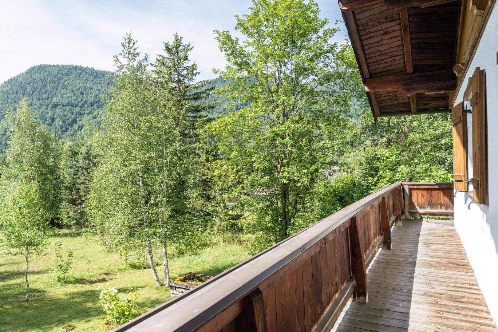 Geräumiger Holzbalkon mit Blick auf die umliegenden Wälder und Berge, ideal zum Entspannen.