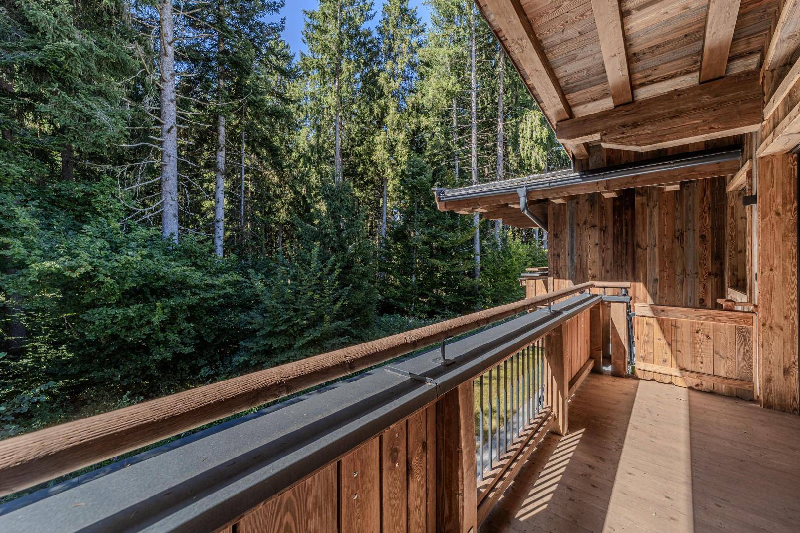 Geräumiger Holzbalkon mit Blick auf den dichten Wald, ideal für Ruhe und Entspannung.
