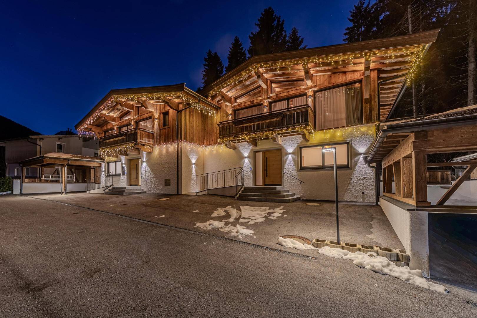 Winterliche Ansicht des Chalets bei Nacht, mit festlicher Beleuchtung und Spuren von Schnee.