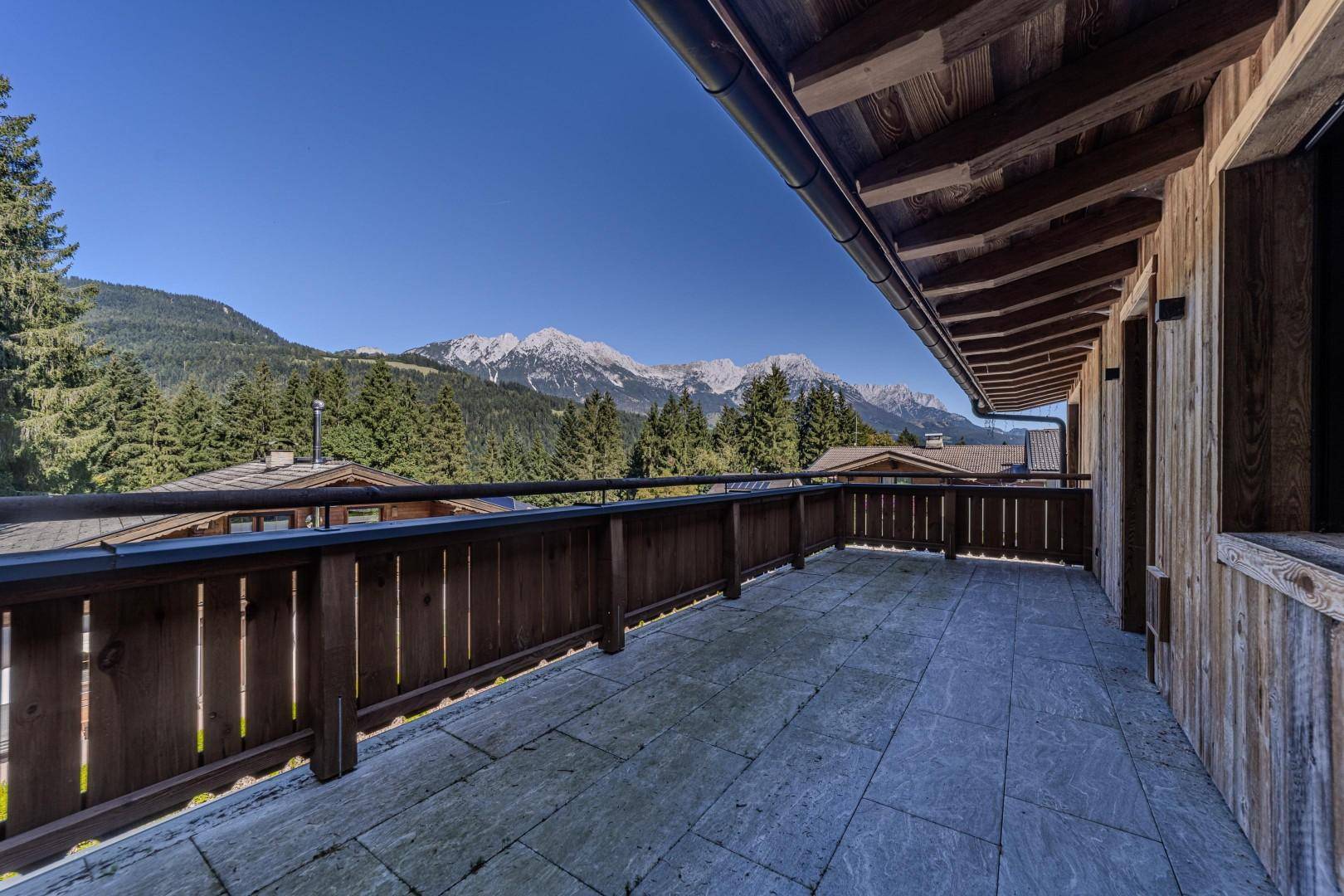 Großer Holzbalkon mit atemberaubendem Bergblick und viel Platz für Outdoor-Möbel.