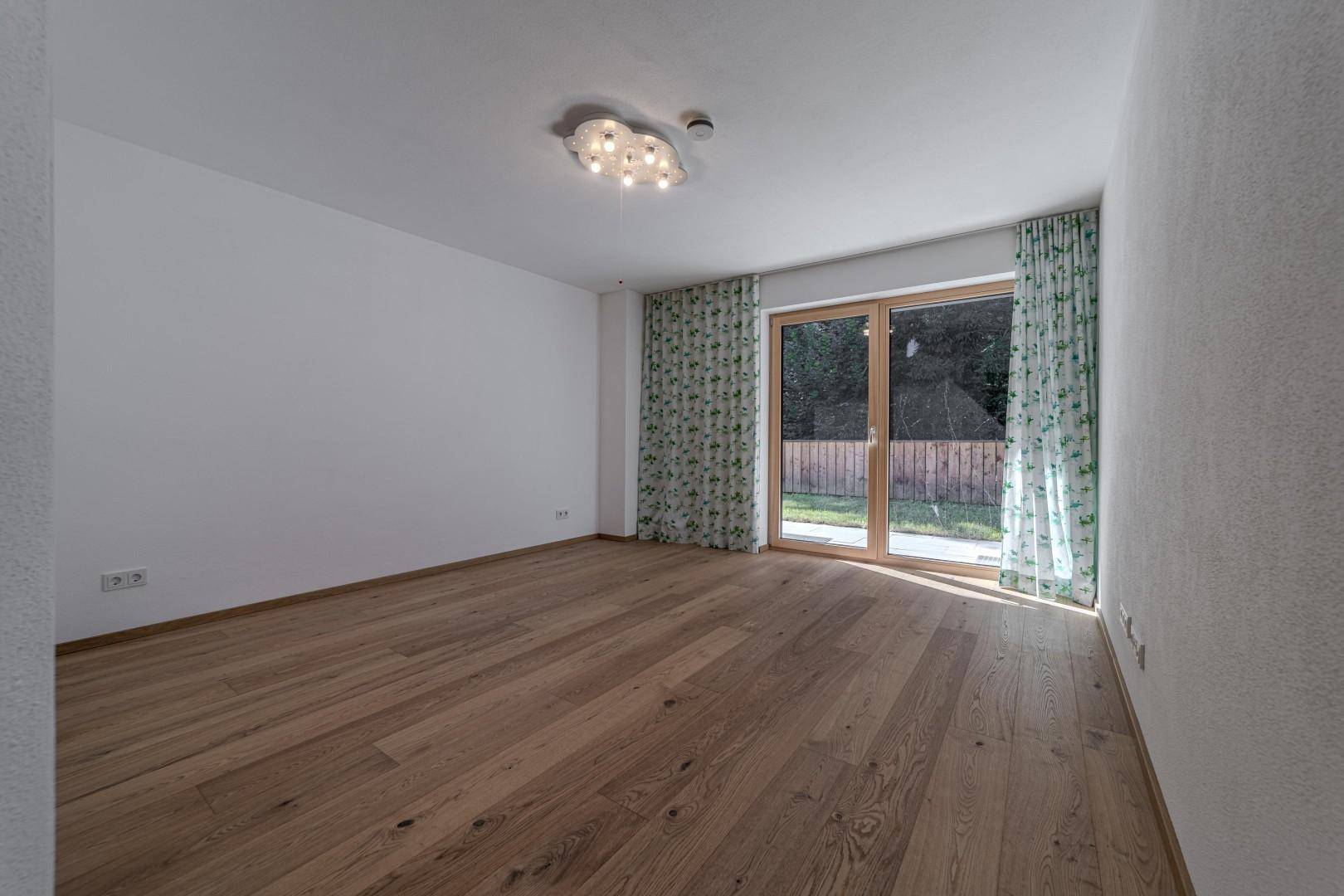 Helles Schlafzimmer mit Holzboden und Zugang zu einem kleinen Außenbereich, bereit zur Einrichtung.