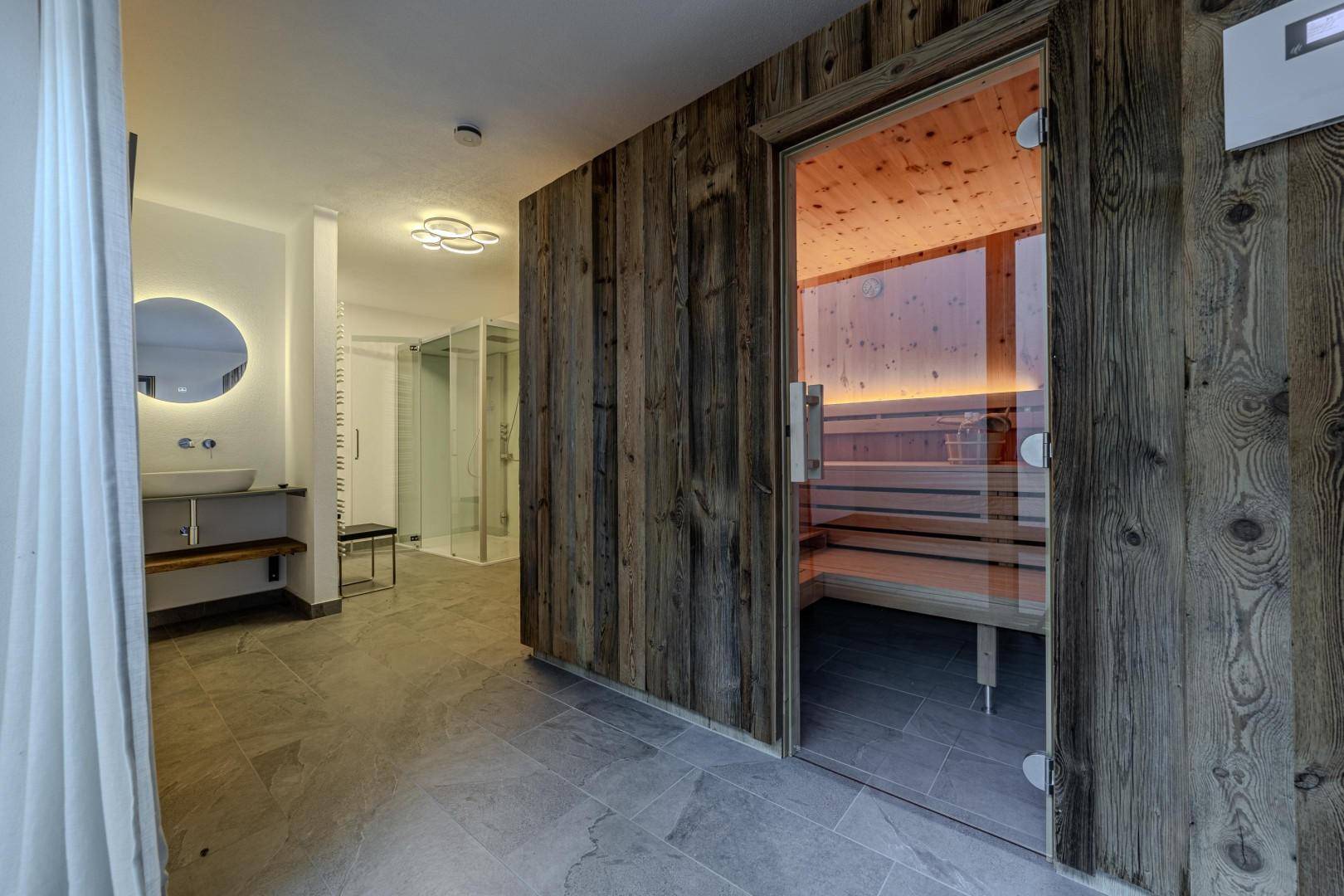Moderner Wellnessbereich mit Sauna, Dusche und Waschbecken, ideal zur Entspannung.