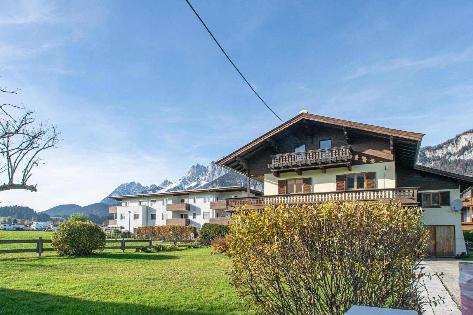 Alpines Haus mit Garten, Balkonen und beeindruckendem Bergblick im Herbst.
