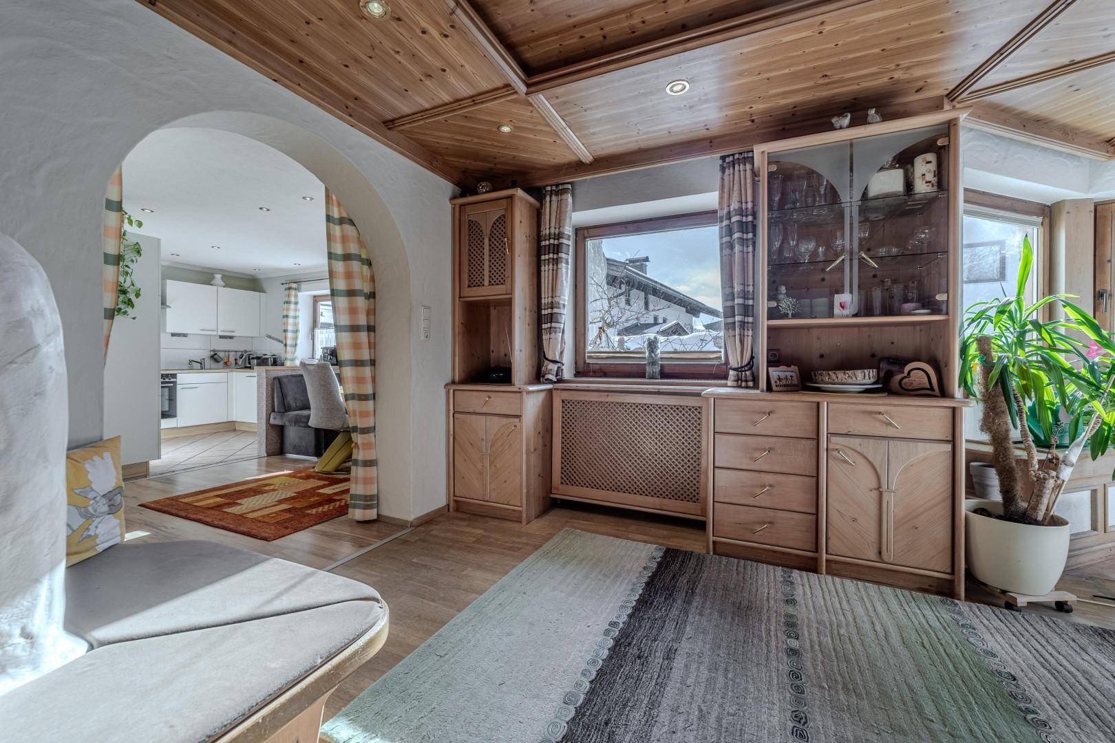 Gemütlicher Wohnbereich mit viel Holz, traditionellen Möbeln und offenem Zugang zur Küche.