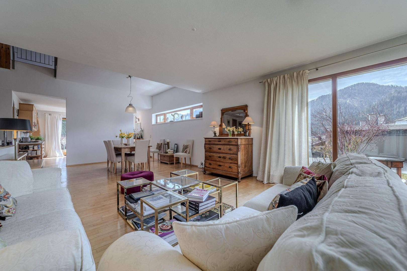 Helles Wohnzimmer mit bequemen Sofas, Holzboden und weitem Blick auf die Berge.