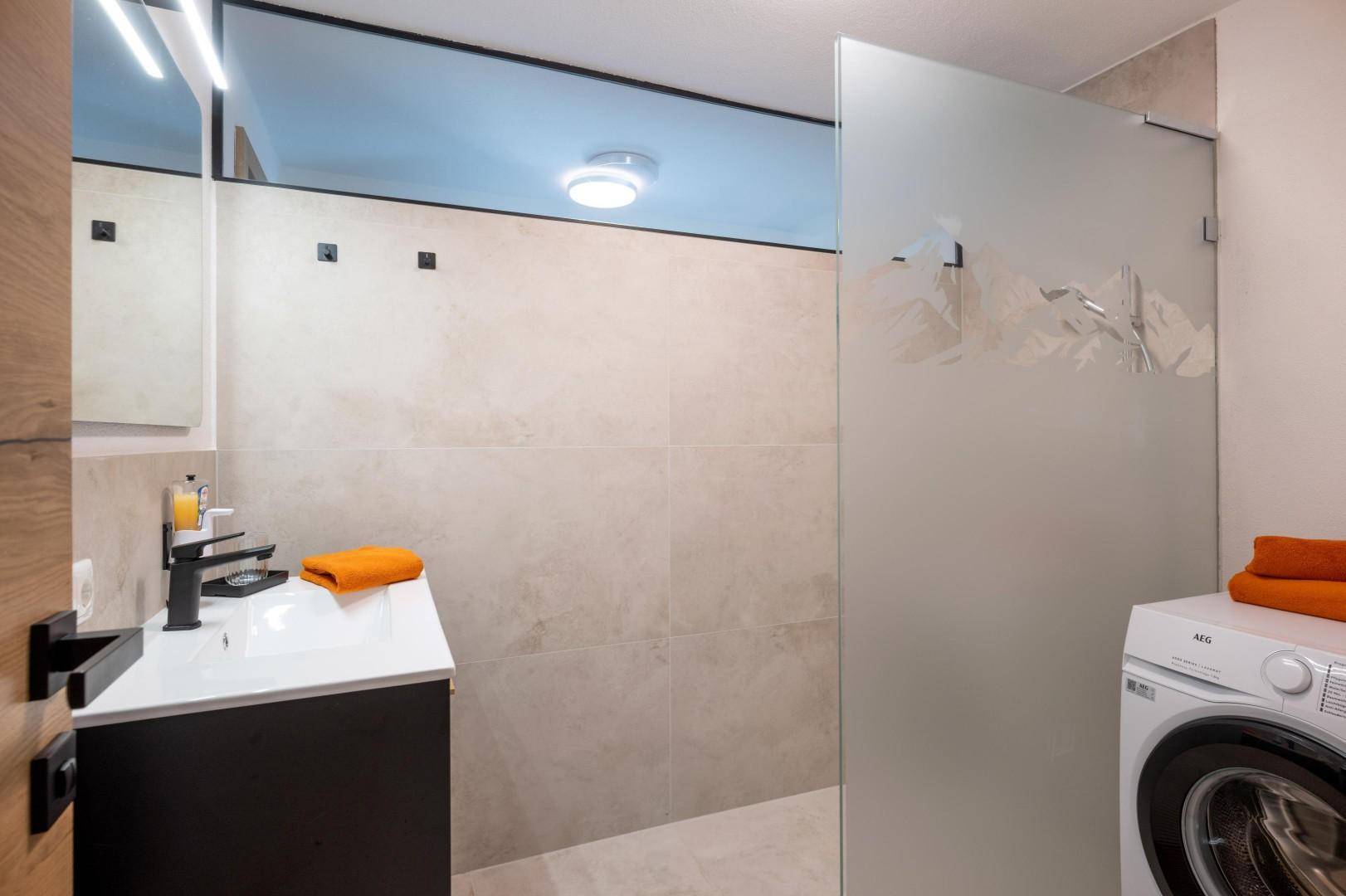 Modernes Badezimmer mit Dusche, Waschmaschine und stilvollem Waschtisch.