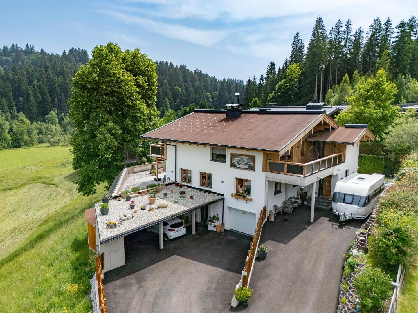 Charmantes Haus in alpiner Landschaft mit Carport, Balkonen und weitem Bergblick.