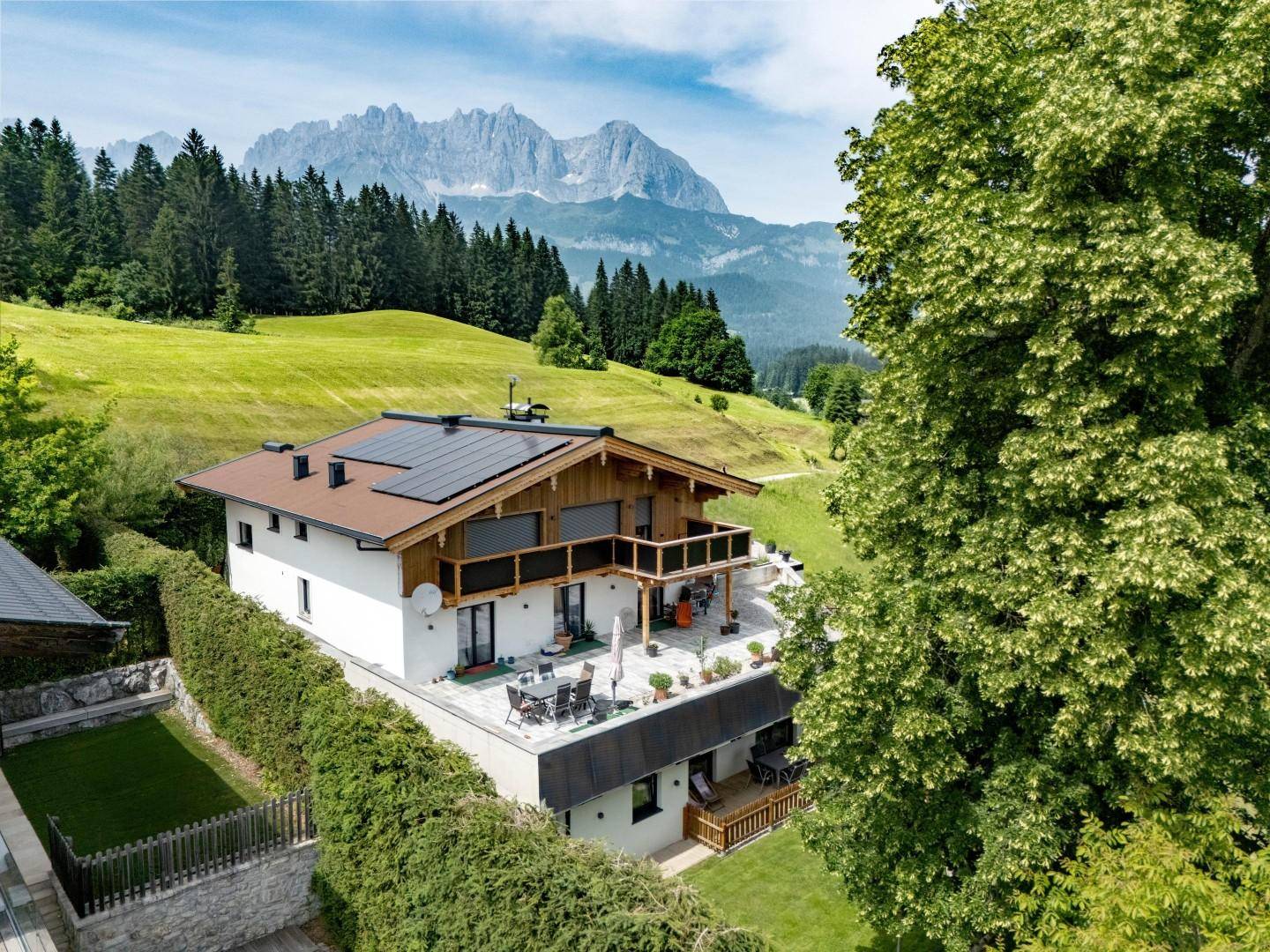 Großzügige Terrasse mit Sitzgelegenheiten, Bergblick und Photovoltaikanlage auf dem Dach.