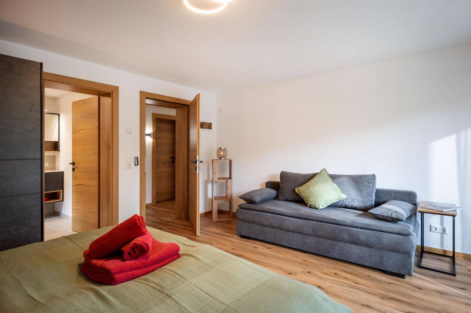 Komfortables Schlafzimmer mit Schlafsofa und Zugang zu einem modernen Badezimmer.