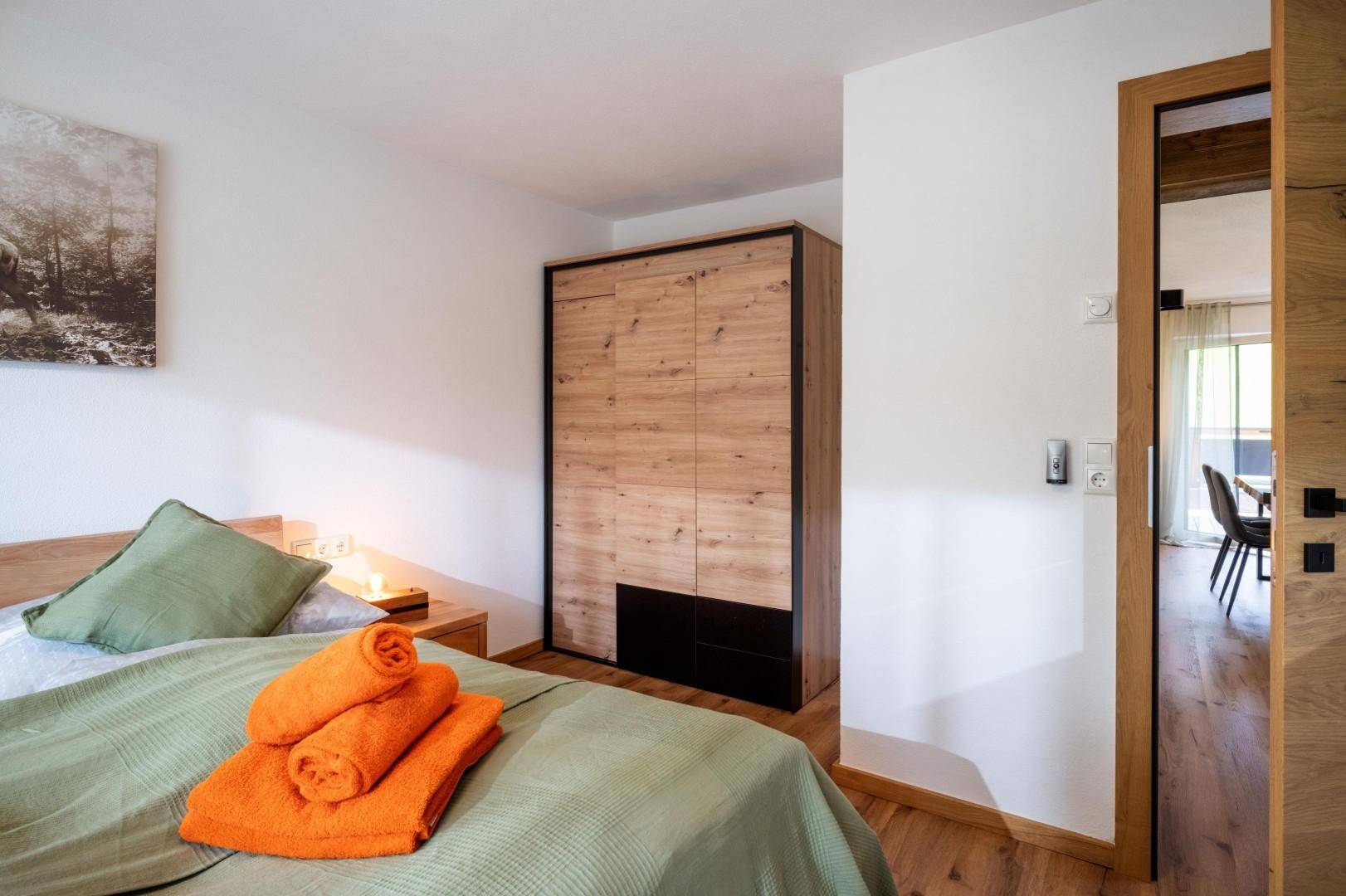 Schlafzimmer mit modernem Kleiderschrank und Holzboden, bietet direkten Zugang zu weiteren Räumen.