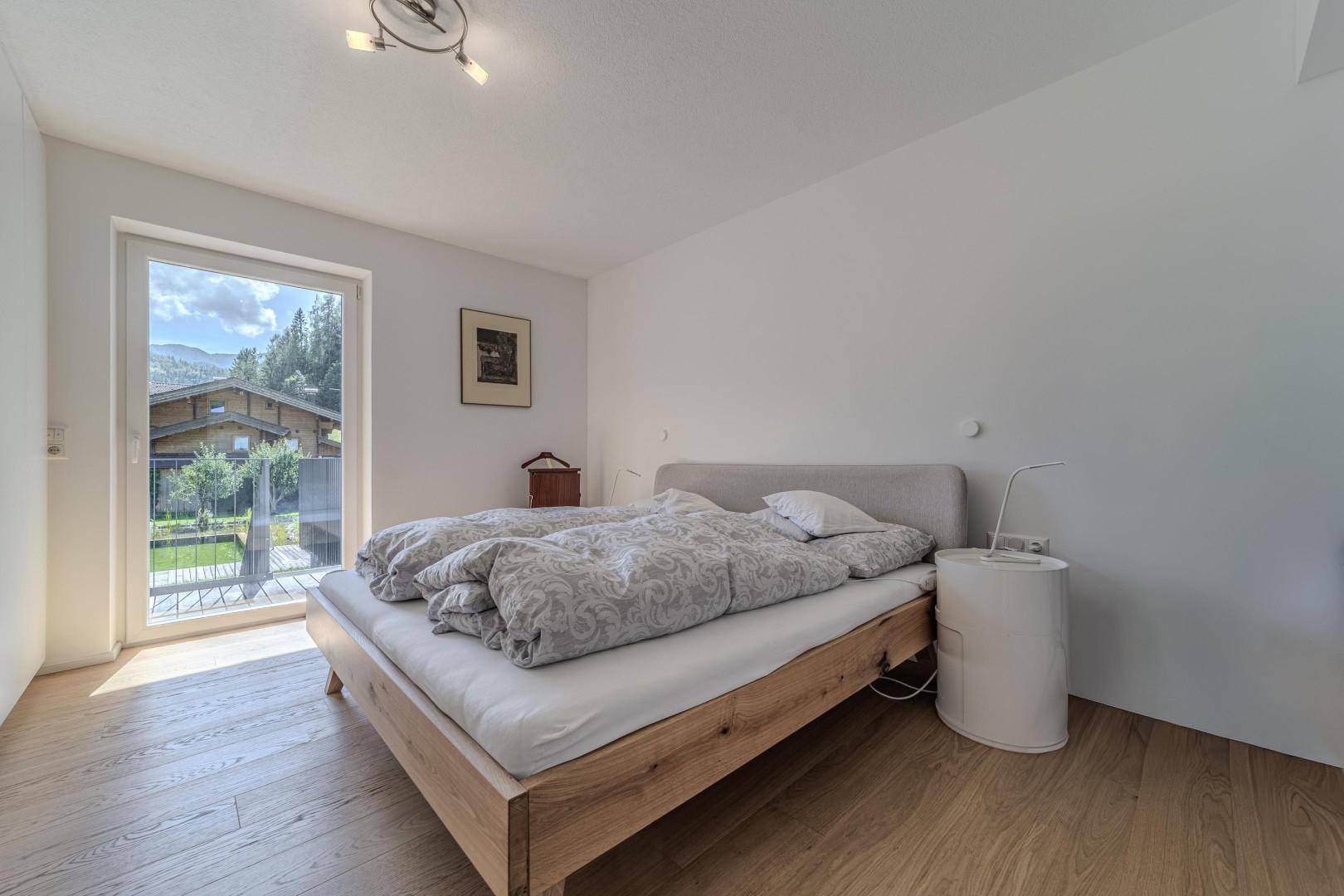 Schlafzimmer mit Holzbett und direktem Zugang zum Balkon mit Bergblick.