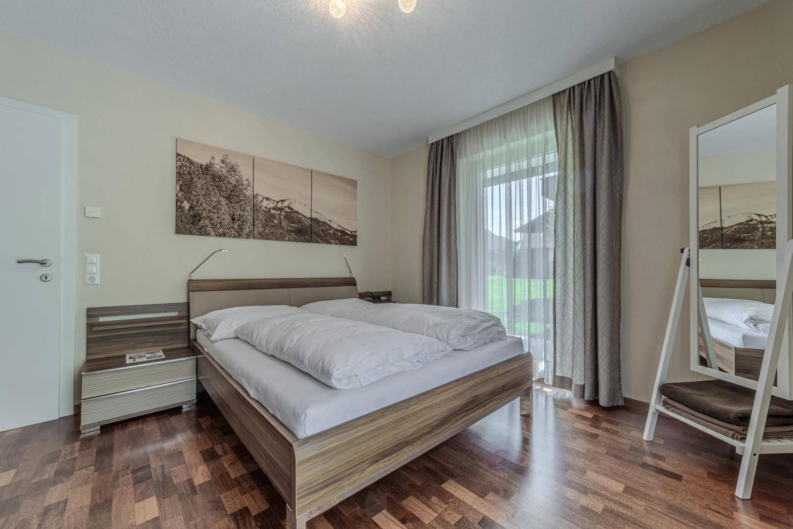 Gemütliches Schlafzimmer mit Doppelbett, Nachttischen und Blick ins Grüne vom Fenster aus.