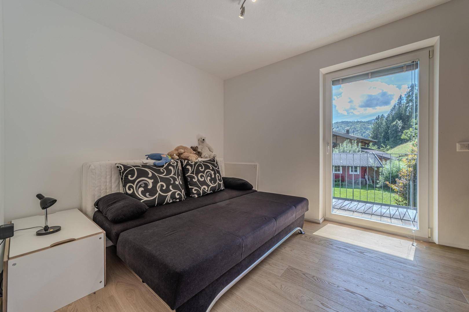Schlafzimmer mit Schlafsofa und Zugang zu einem kleinen Balkon mit Bergblick.