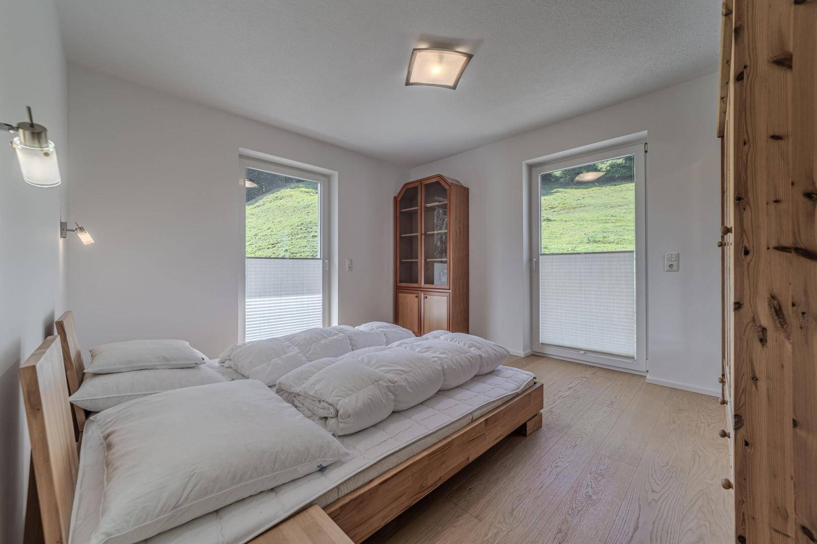 Gemütliches Schlafzimmer mit zwei Einzelbetten, Holzschrank und Blick ins Grüne.