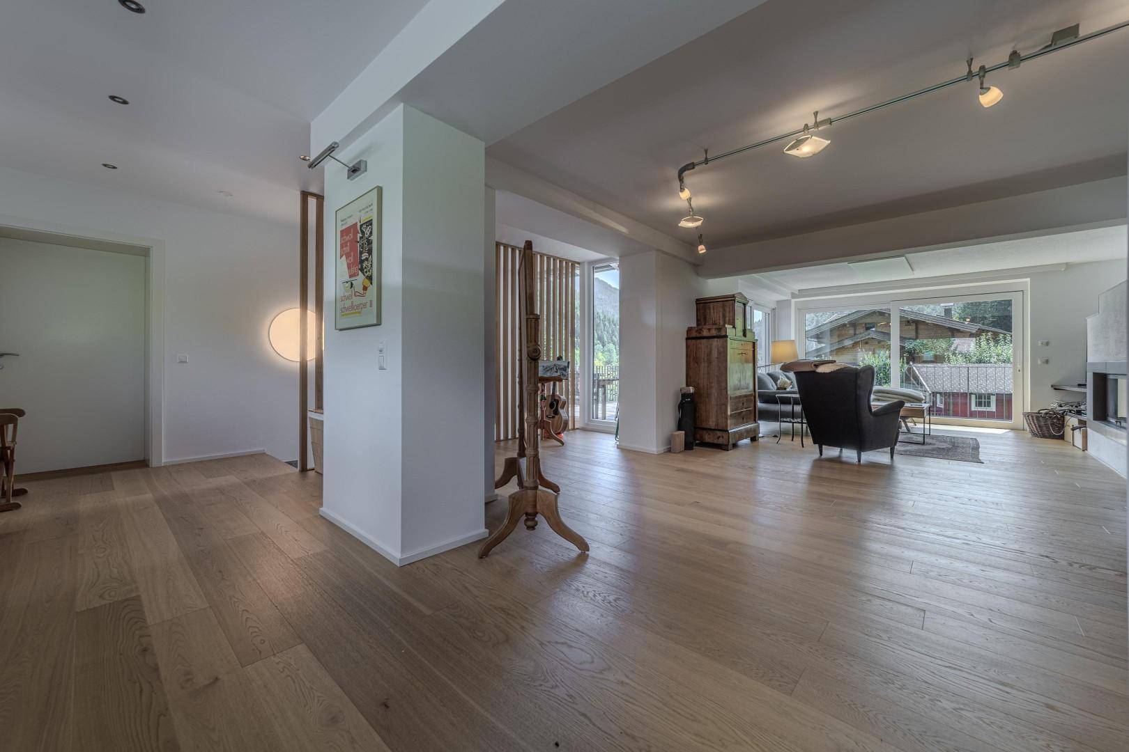 Heller Eingangsbereich mit Holzboden, moderner Beleuchtung und Zugang zum Wohnzimmer.