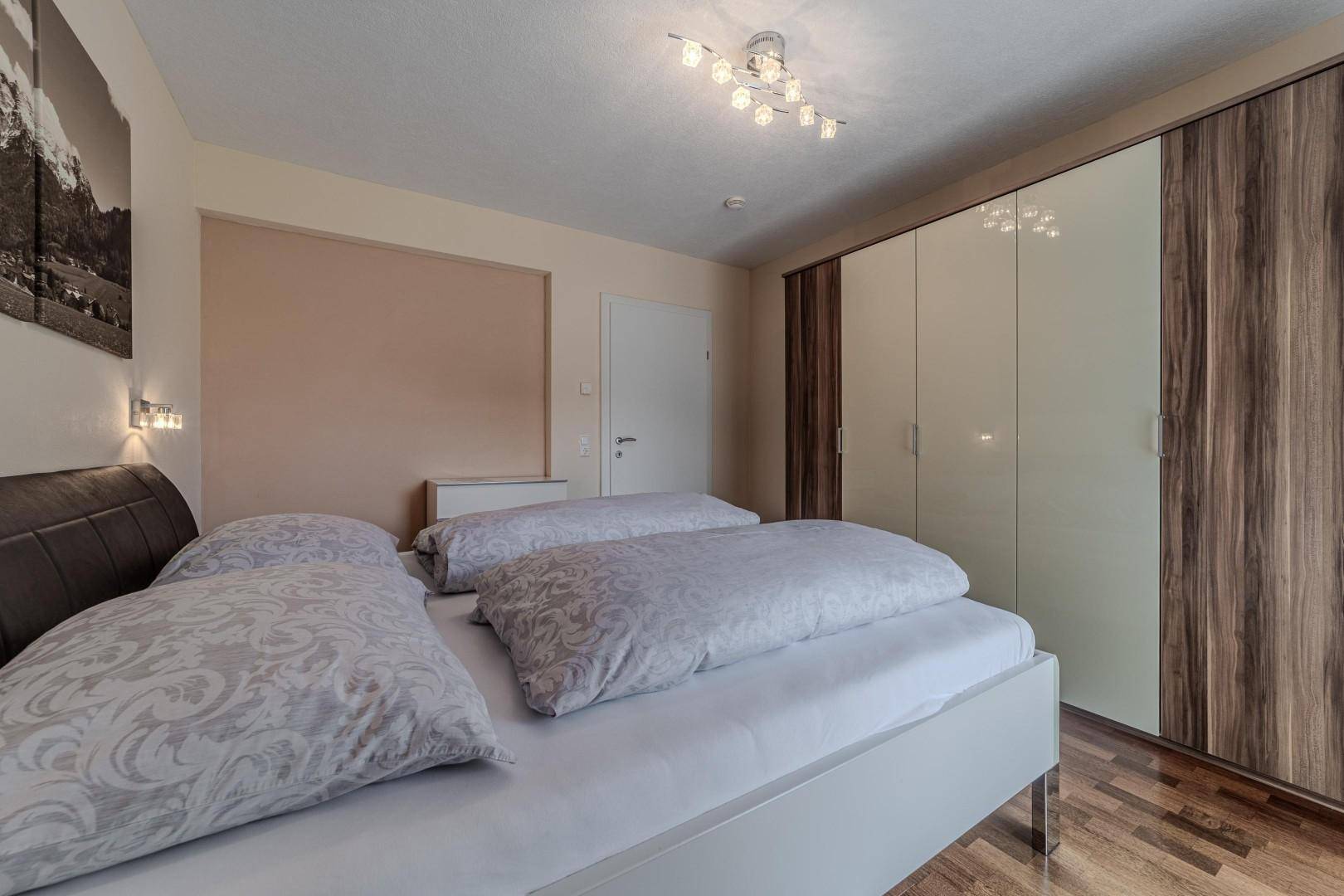 Schlafzimmer mit Doppelbett und großem Kleiderschrank, bietet eine ruhige Atmosphäre.