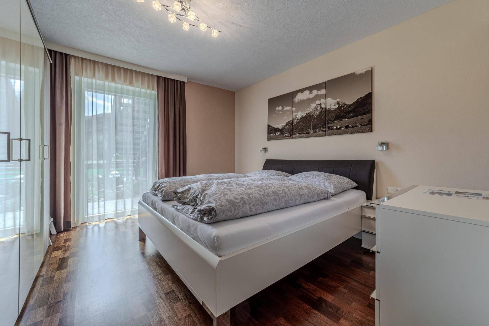 Schlafzimmer mit Doppelbett, Kleiderschrank und Zugang zu einem Balkon.