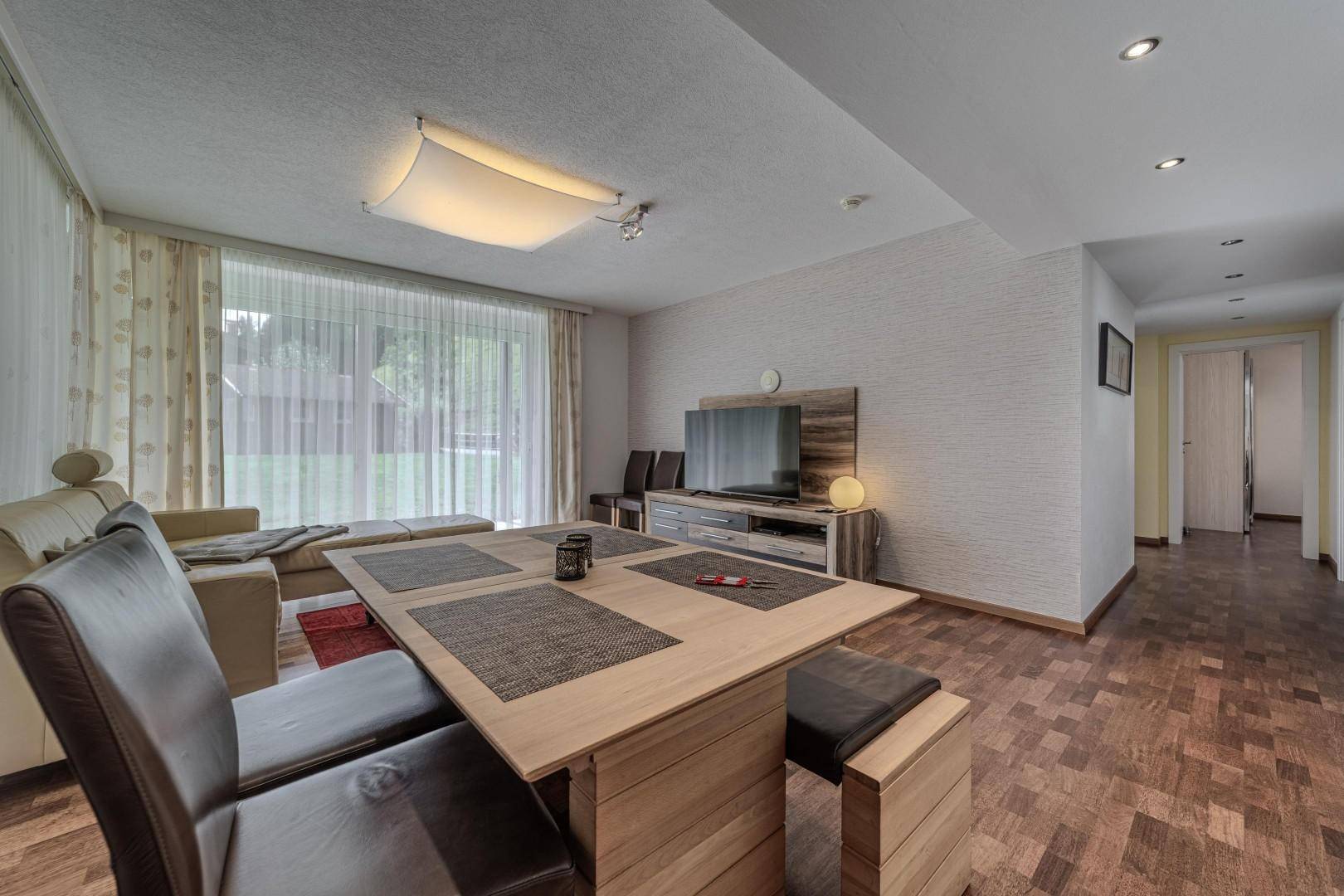Geräumiger Wohn- und Essbereich mit Holzboden, großem Esstisch und Sofa.
