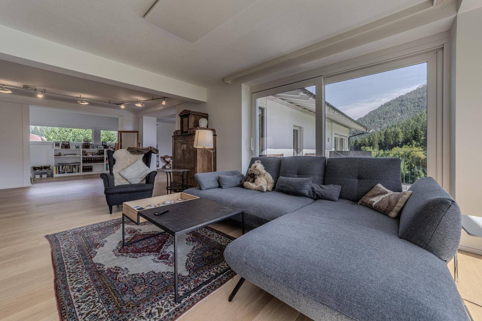 Komfortables Ecksofa im Wohnzimmer mit Blick auf die grüne Berglandschaft.