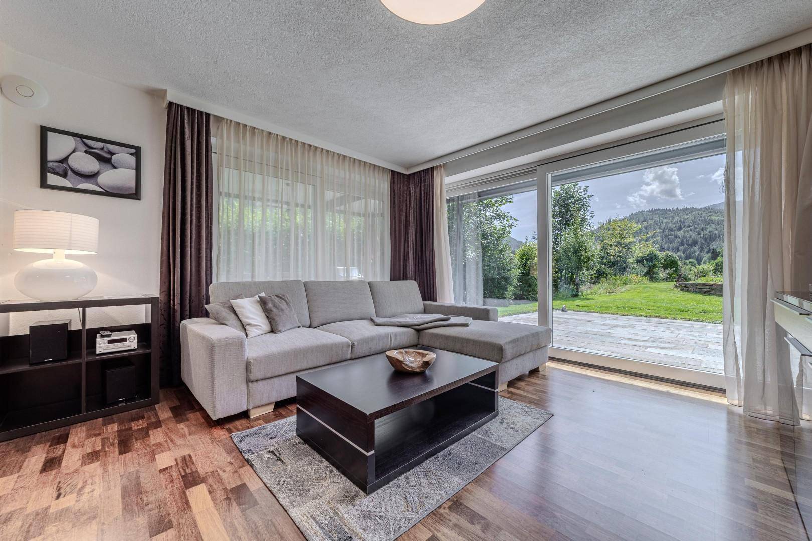 Gemütliches Wohnzimmer mit großem Sofa, Couchtisch und Schiebetür zum Garten.