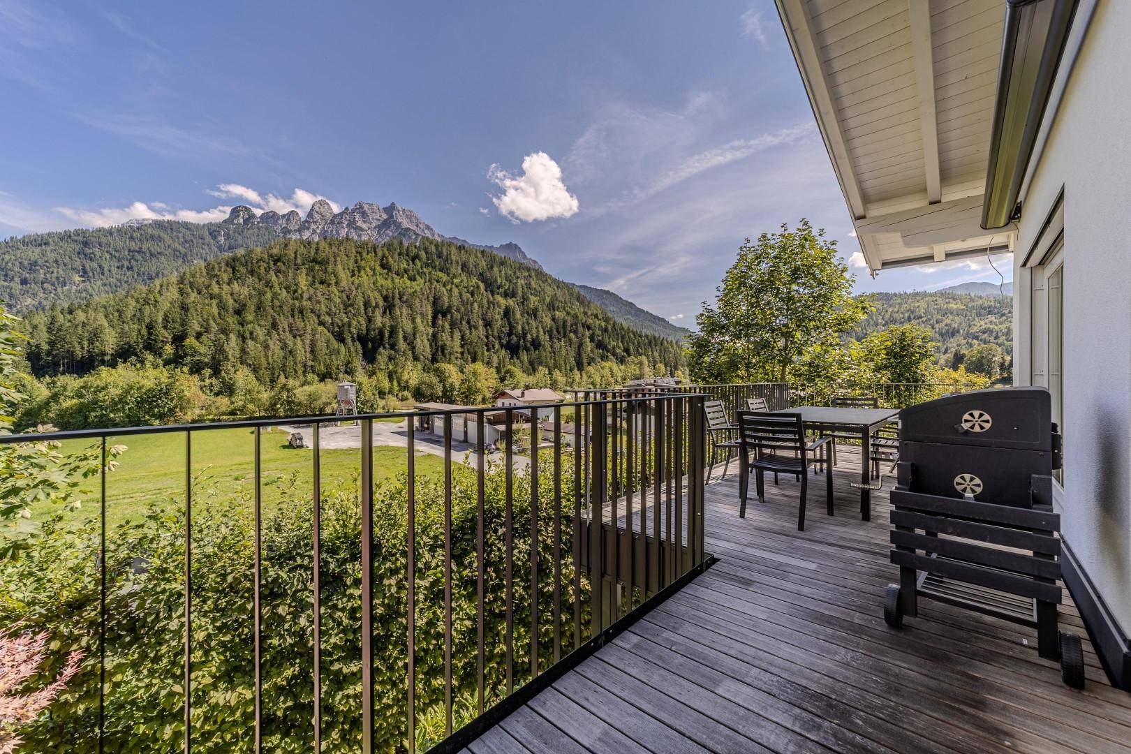 Großer Balkon mit Esstisch, Grill und Panoramablick auf die Berge und das Tal.