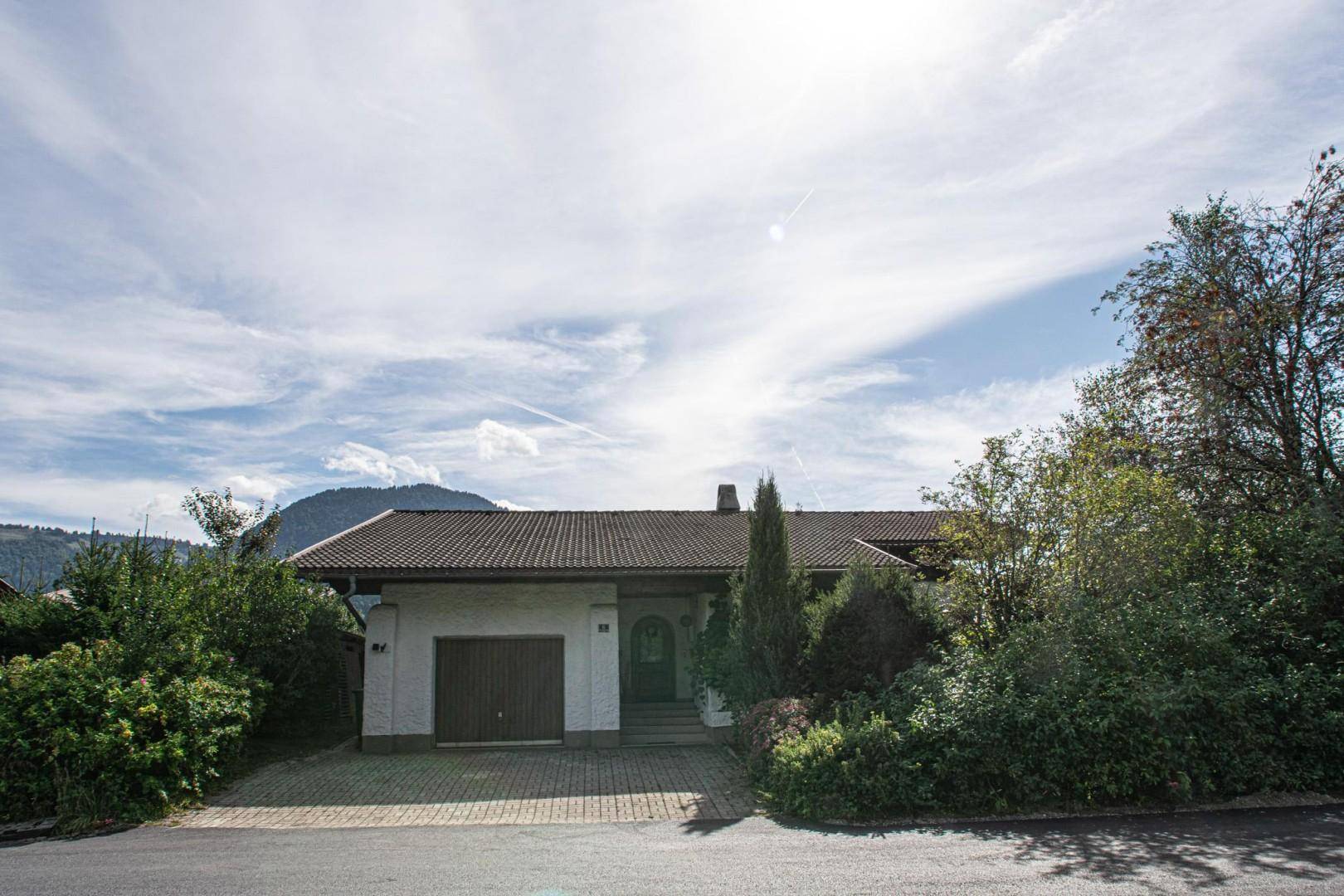 Vorderansicht des Hauses mit integrierter Garage und gepflasterter Einfahrt.