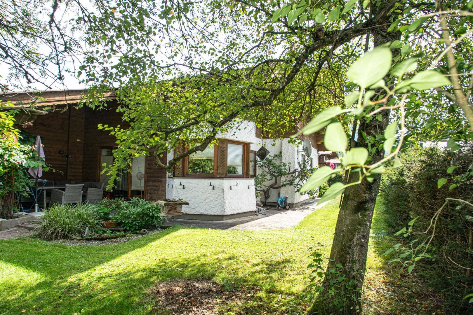 Gemütlicher Gartenbereich mit Terrasse und Sitzgelegenheiten unter einem Baum.