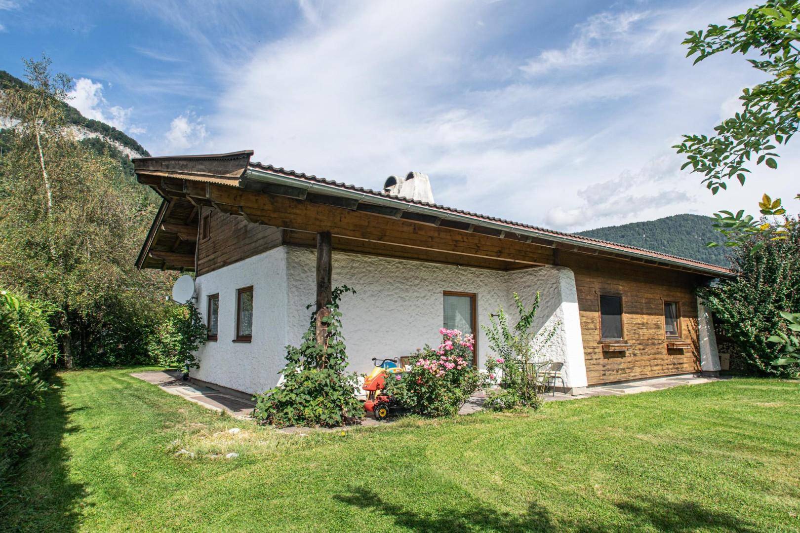 Seitlicher Blick auf das Haus mit großem Garten und traditioneller Holzverkleidung.