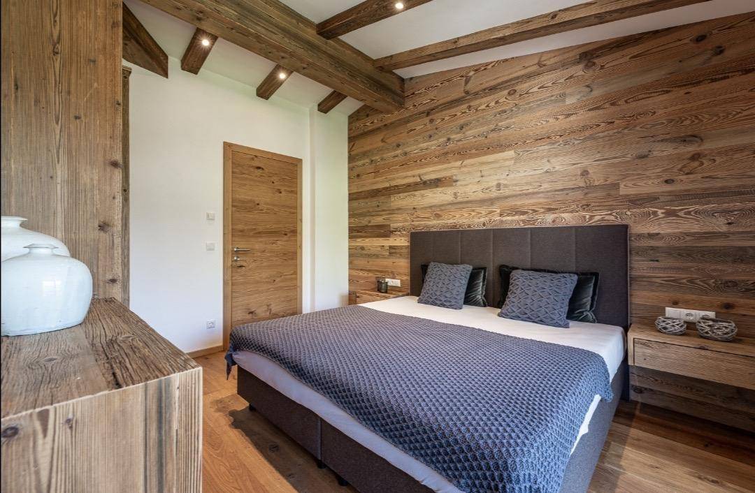 Schlafzimmer mit Holzwandverkleidung, bequemen Bett und passenden Holzmöbeln.