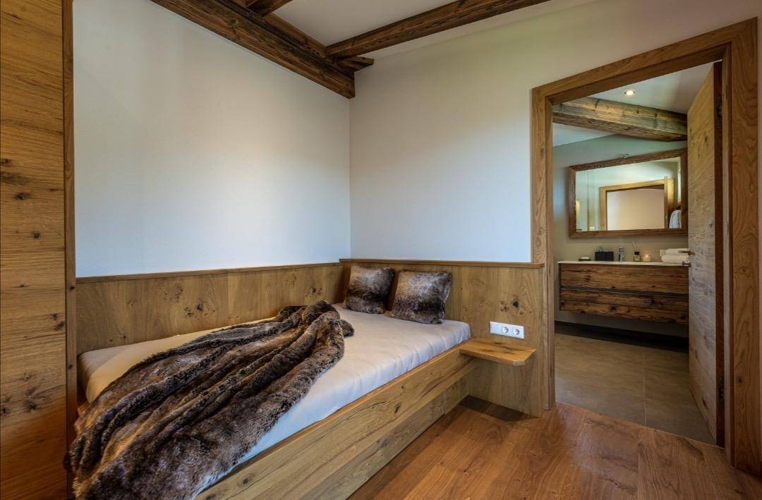 Kleines Schlafzimmer mit Einzelbett, Holzvertäfelung und Blick in das angrenzende Badezimmer.