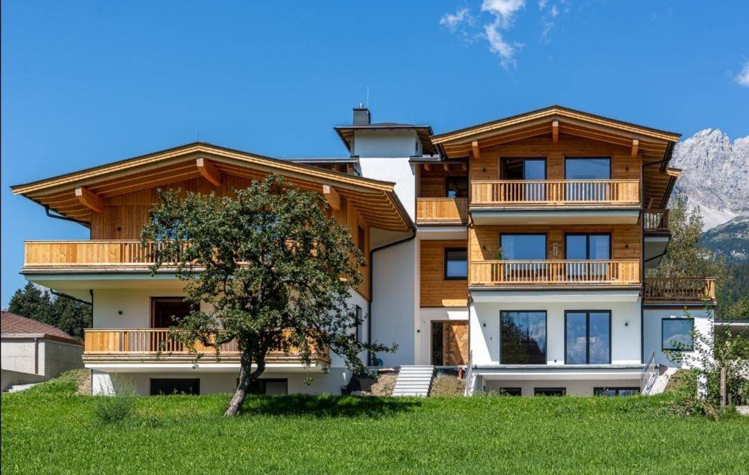 Attraktives modernes Holzhaus mit mehreren Balkonen und Bergblick in ländlicher Umgebung.