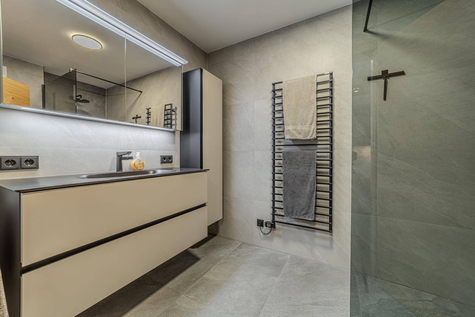 Modernes Badezimmer mit großem Waschtisch, Spiegel und beheiztem Handtuchhalter.