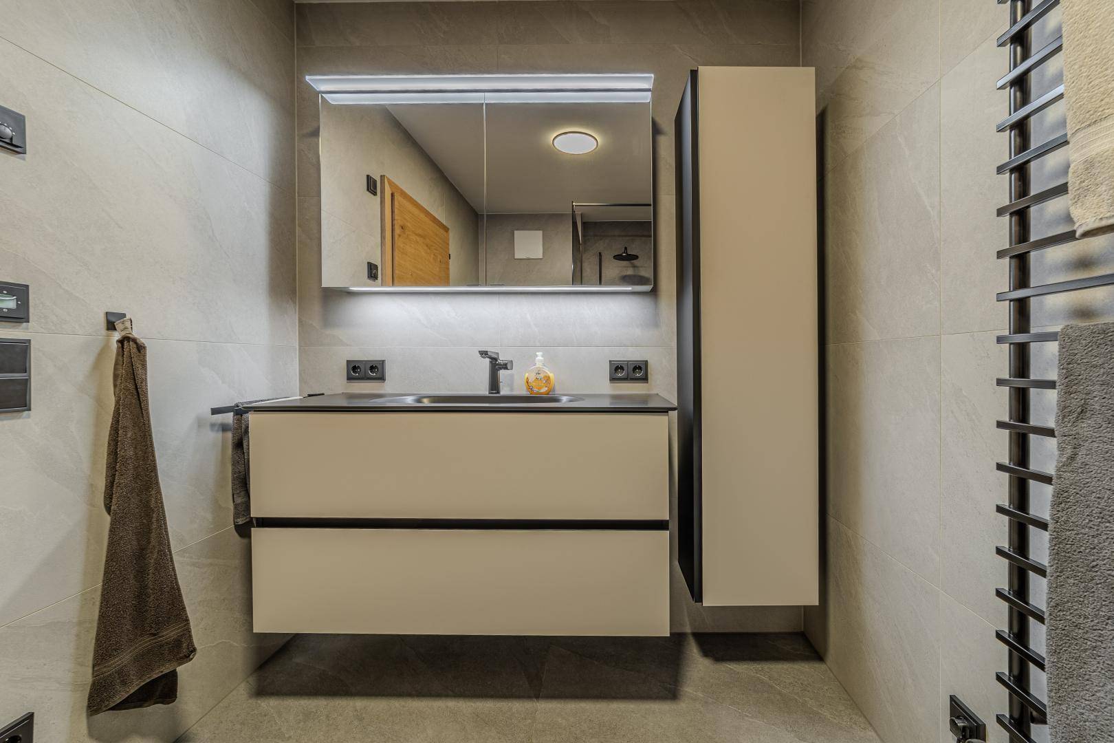 Elegantes Badezimmer mit schwebendem Waschtisch, großem Spiegelschrank und modernen Armaturen.