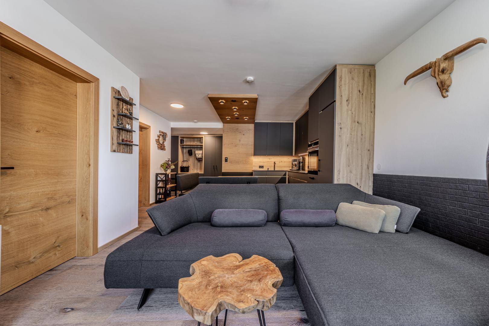 Gemütlicher Wohnbereich mit Ecksofa und Blick auf die offene, modern gestaltete Küche.