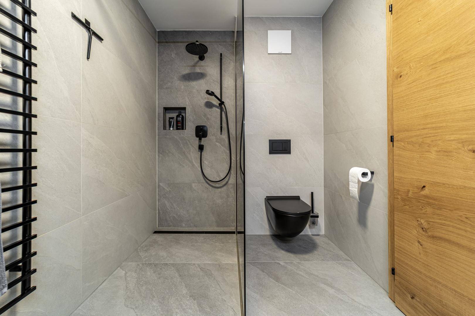 Zeitgemäßes Badezimmer mit ebenerdiger Dusche, schwarzer Wandtoilette und grauen Fliesen.