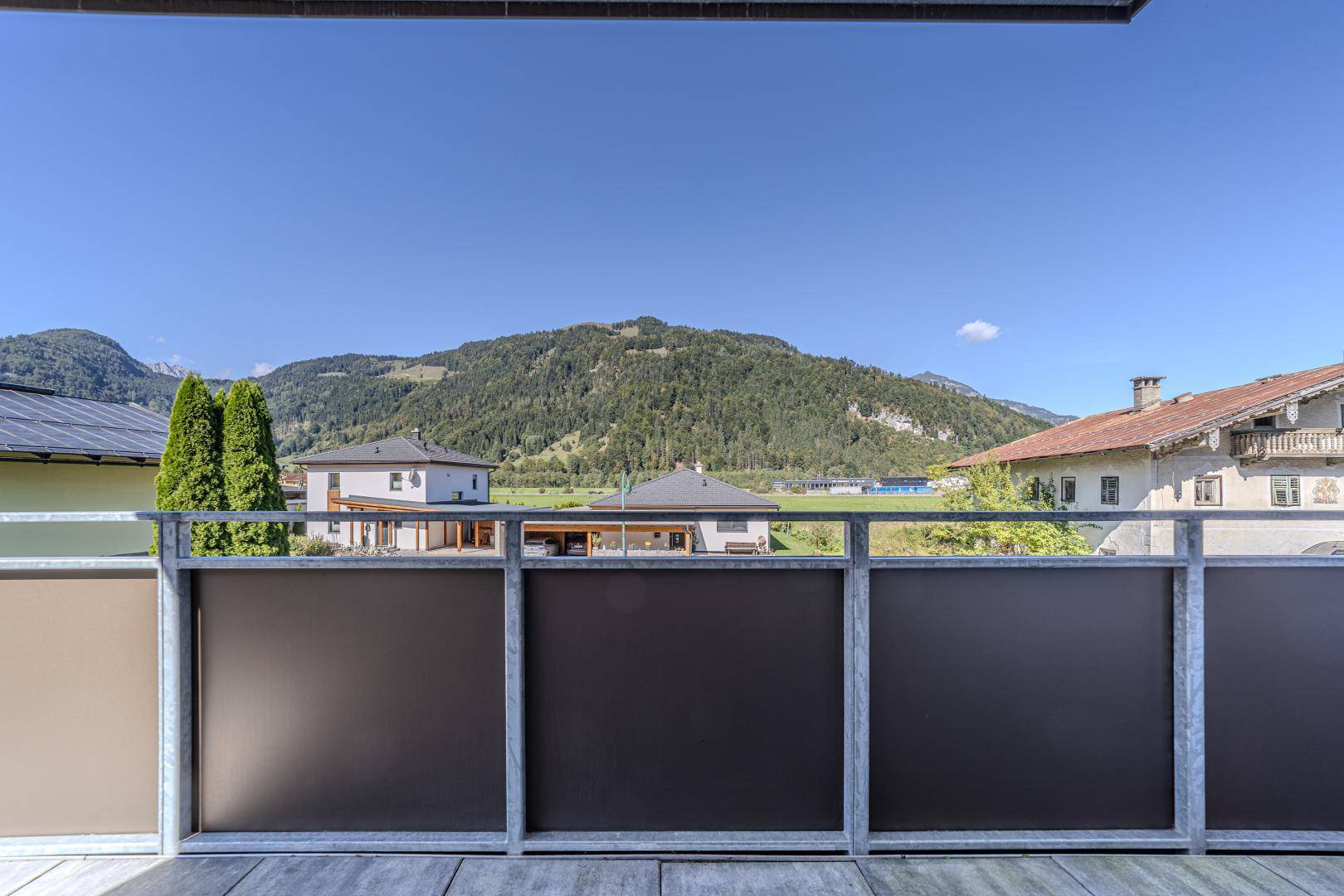 Weitläufiger Blick vom Balkon auf die umliegende Berglandschaft und grüne Umgebung.