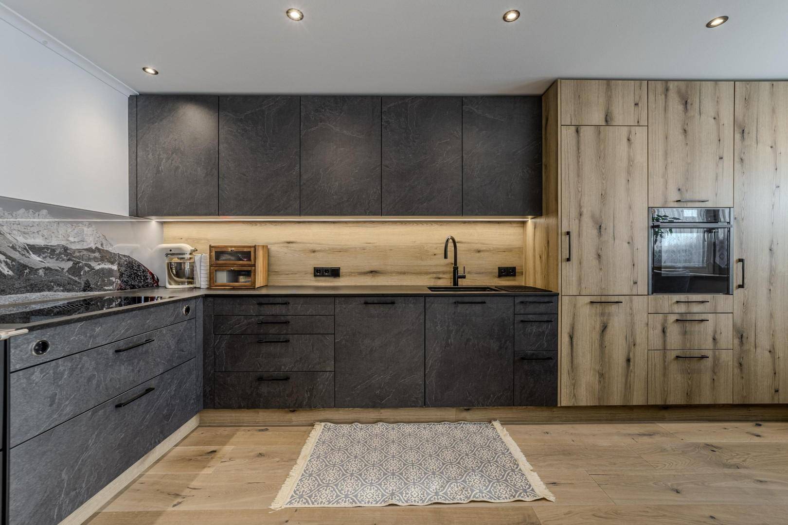 Geräumige moderne Küche mit dunklen und hellen Holzfronten, Holzboden und Einbaugeräten.