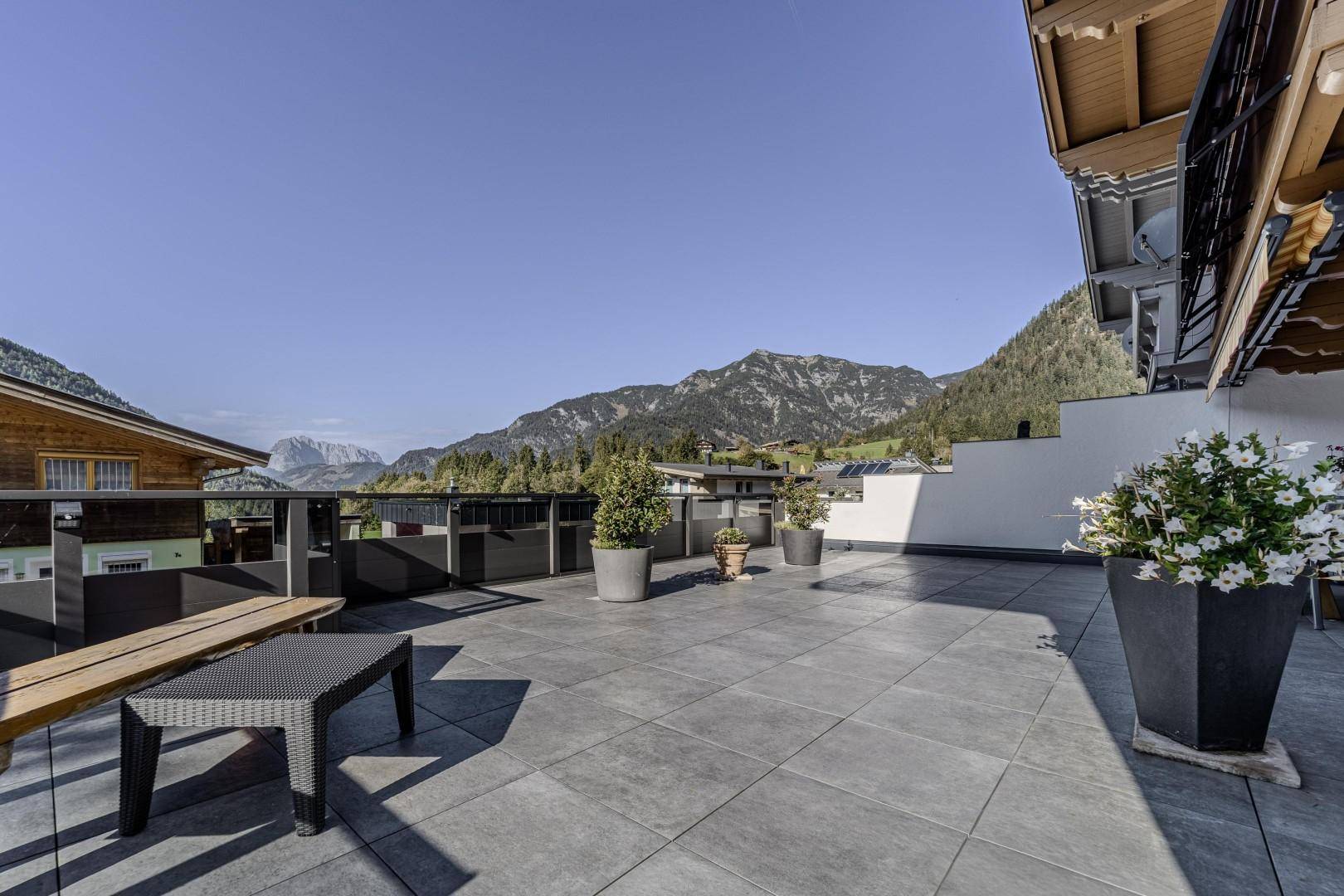 Geräumige Dachterrasse mit Fliesenboden, Sitzgelegenheiten und weitem Bergblick.