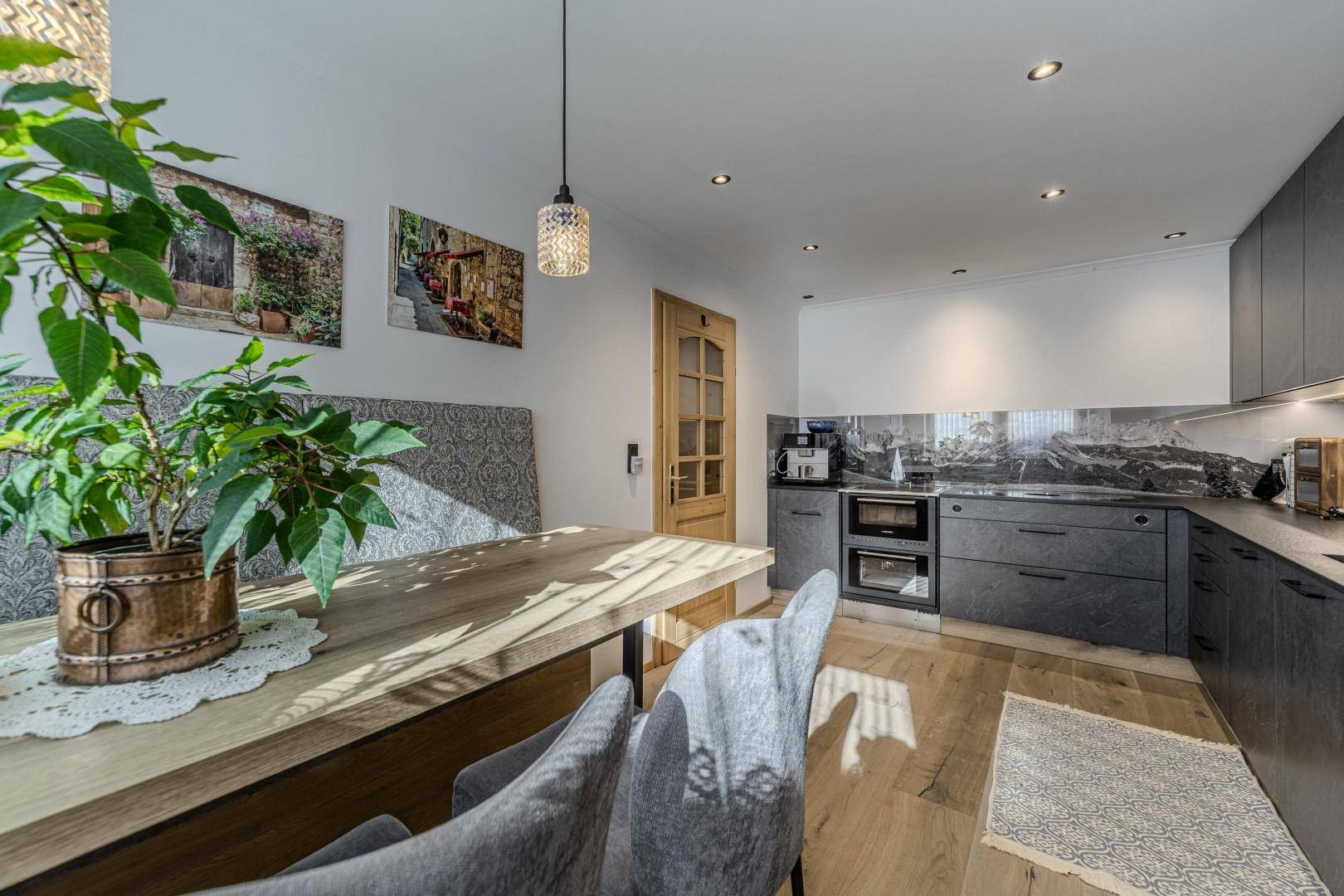Moderne Küche mit Holzboden, integriertem Essbereich und dunklen Schrankfronten.