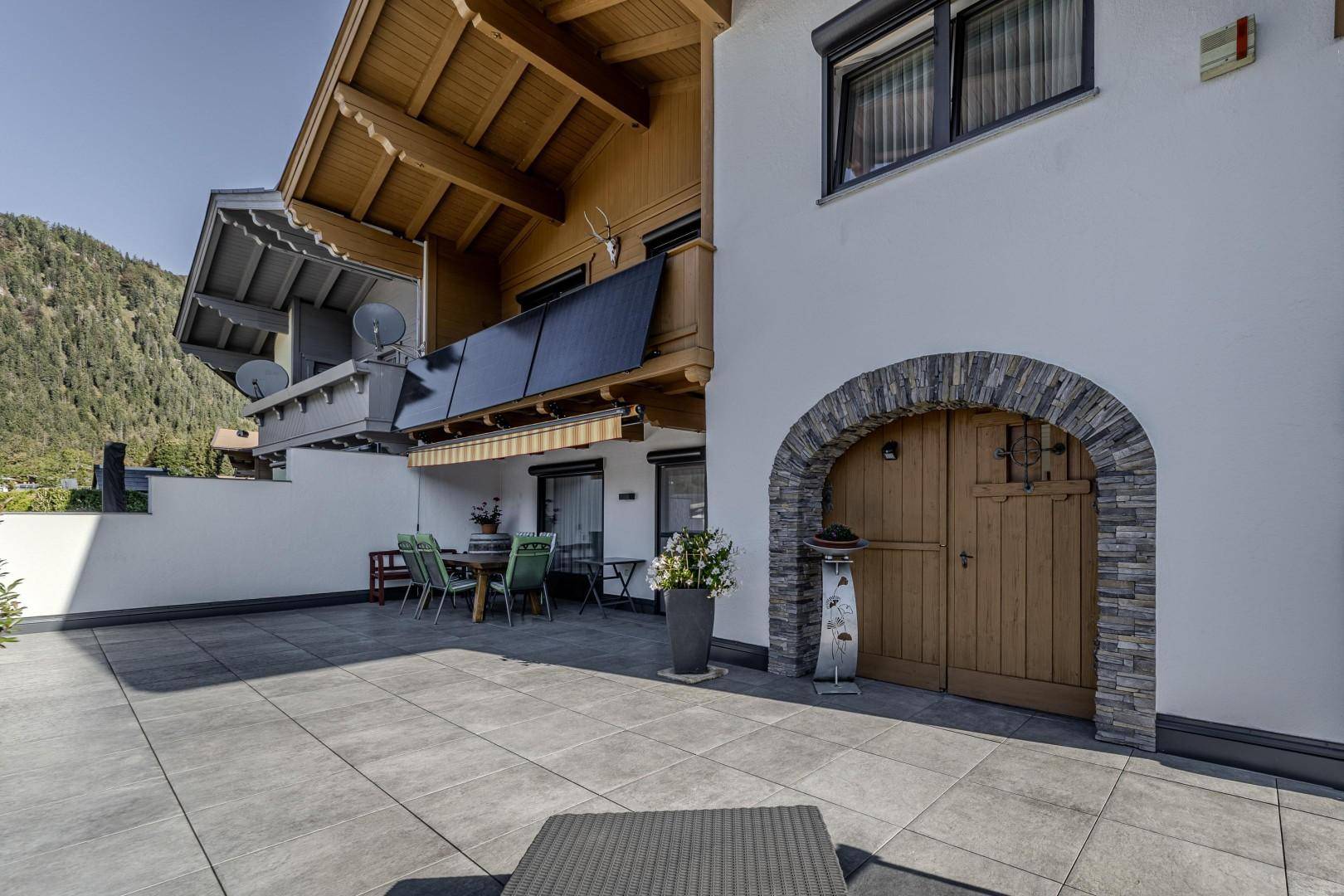 Große gepflasterte Terrasse mit Essbereich im Freien und traditionellem Hauseingang.
