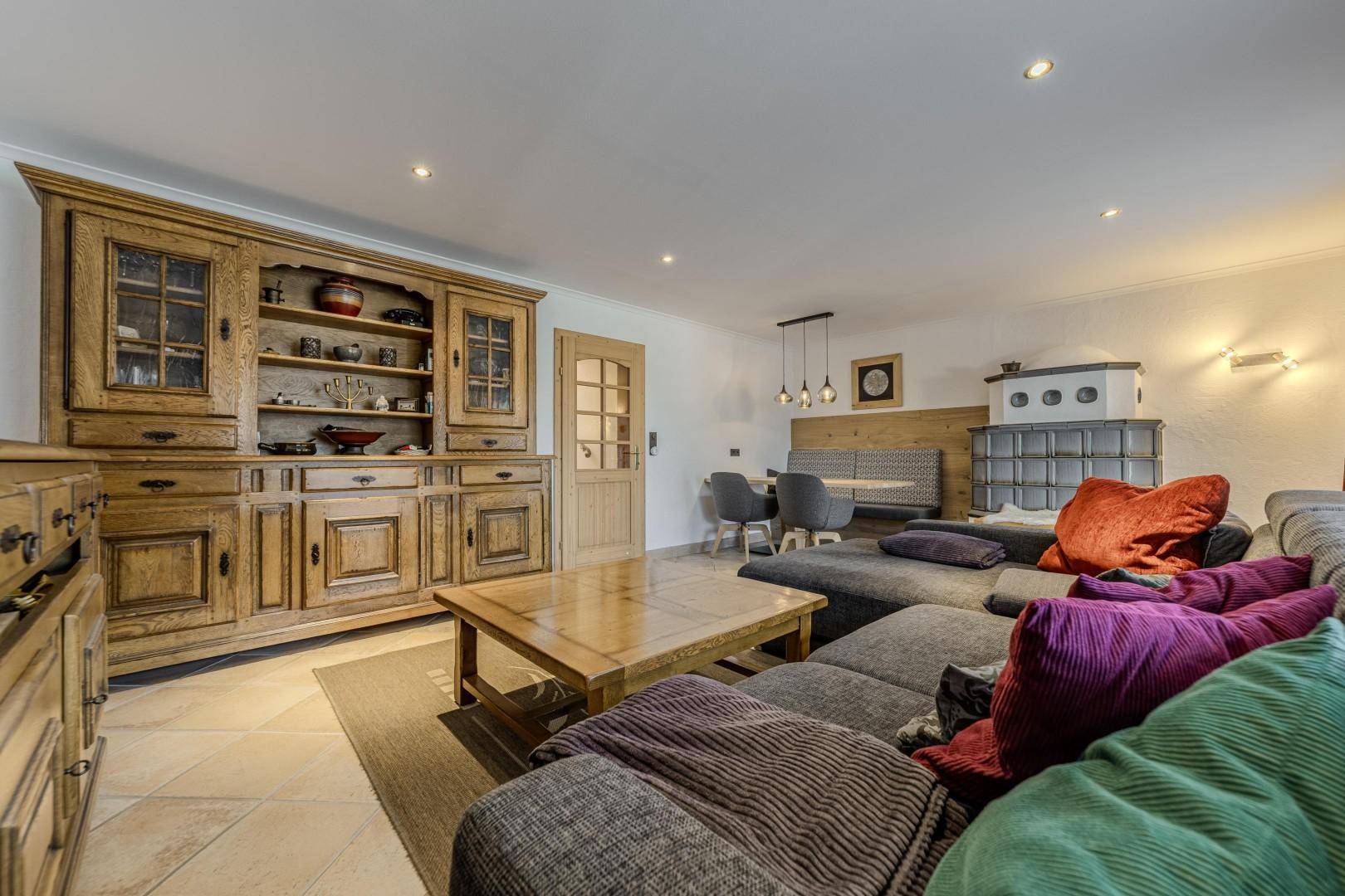 Geräumiger Wohn-Essbereich mit traditionellen Holzmöbeln, Kachelofen und großem Sofa.