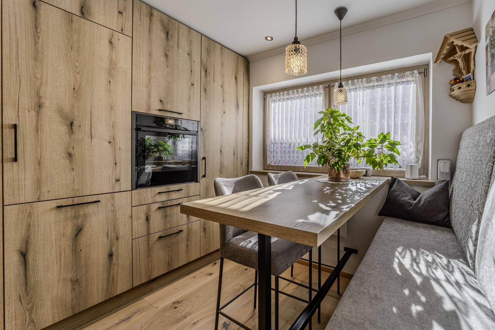 Heller Essbereich in der Küche mit Holztisch, Sitzbank und Fenster.